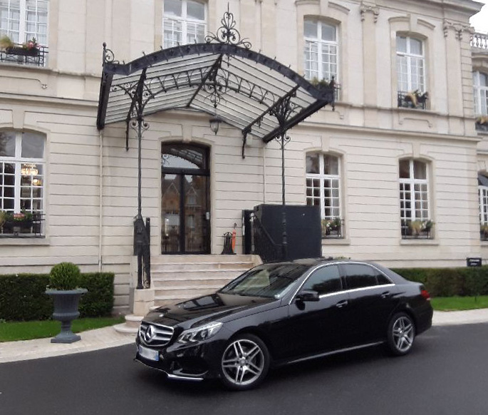 Une voiture de la société H.M Prestige VTC stationnée devant un hôtel particulier